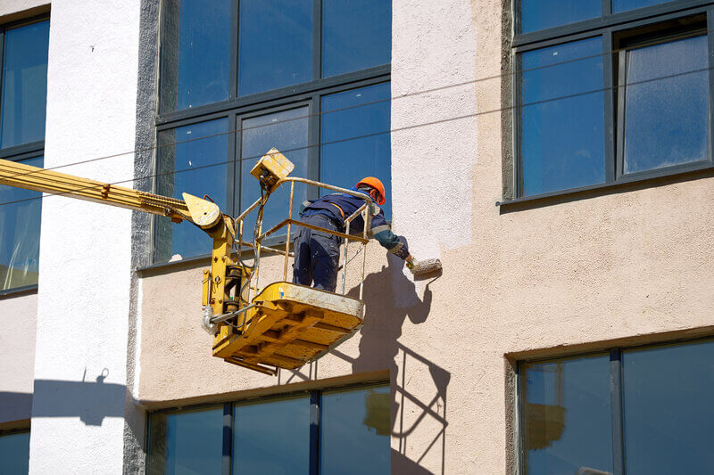 exterior painting on building in hot weather with scissor lift.