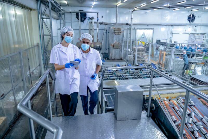 Two food auditors walking up stairs in food factory